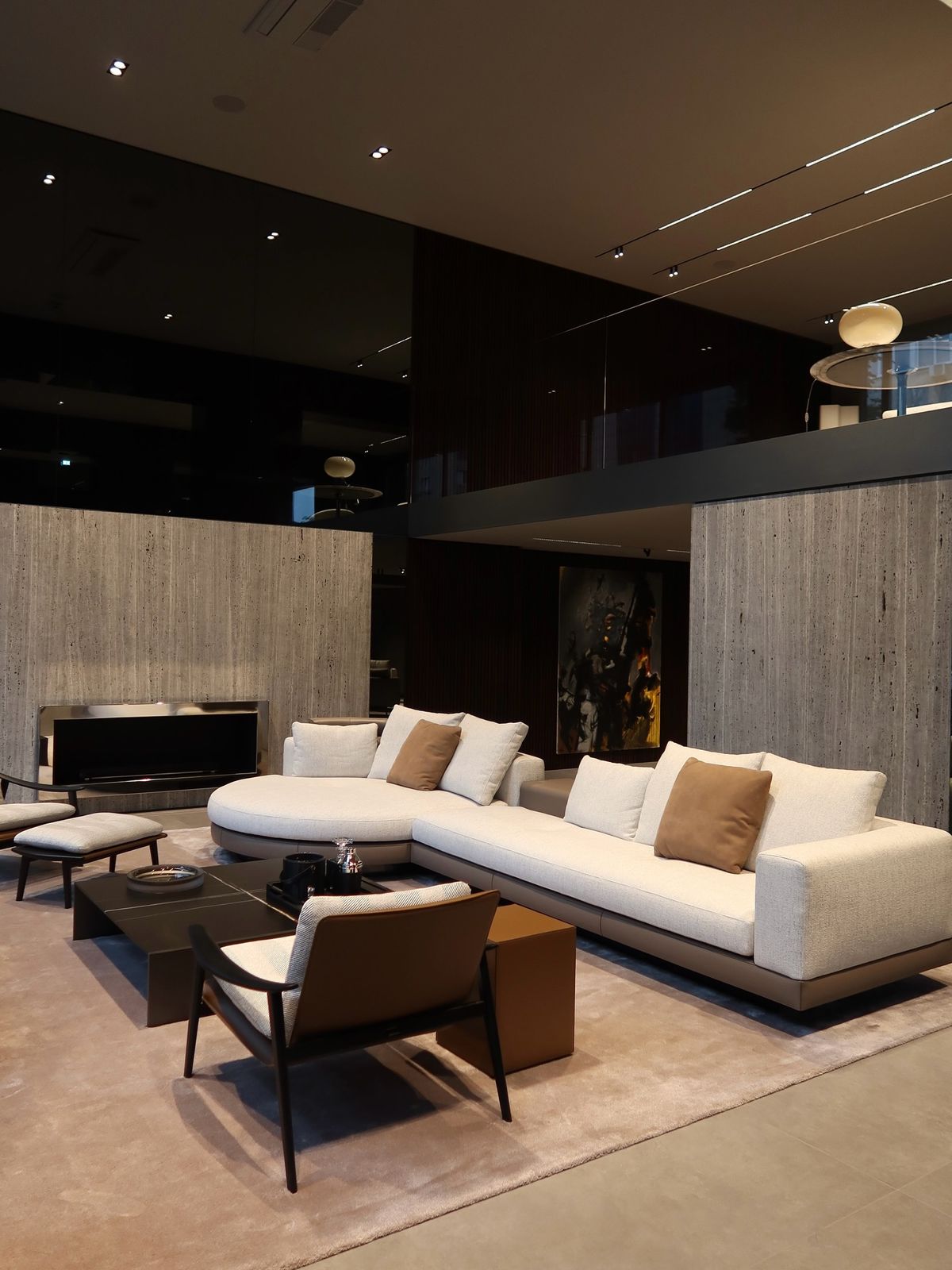 Ivory sectional sofa and leather lounge chair beside travertine walls